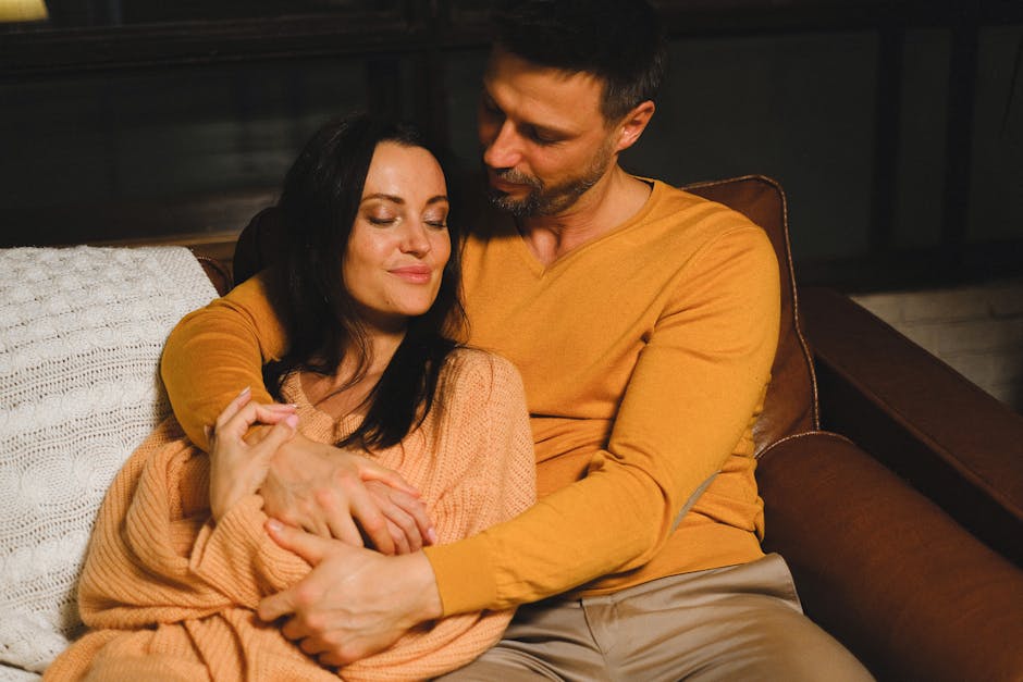 A loving couple embraces on a sofa, wrapped in warm sweaters, exuding a sense of cozy intimacy.