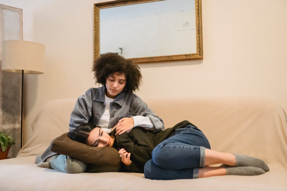 Full body of calm young African American lady in casual clothes cuddling sad female best friend lying on sofa and crying