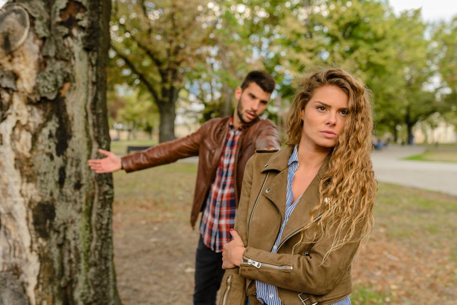 A man and woman in a heated argument outdoors, expressing emotions.