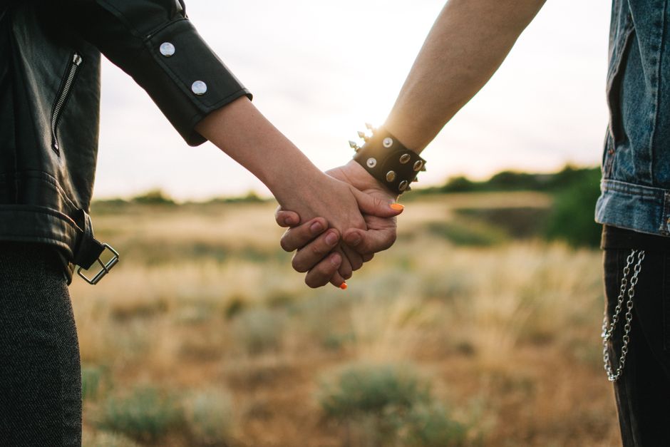 A couple holding hands in a scenic field, symbolizing love and connection.
