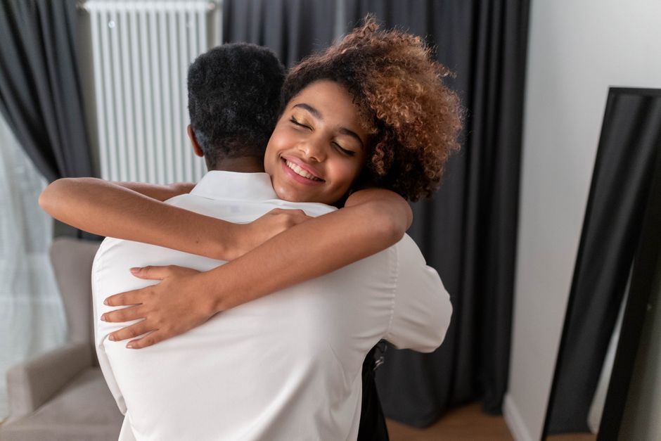 A joyful indoor hug between a parent and daughter, expressing love and happiness.