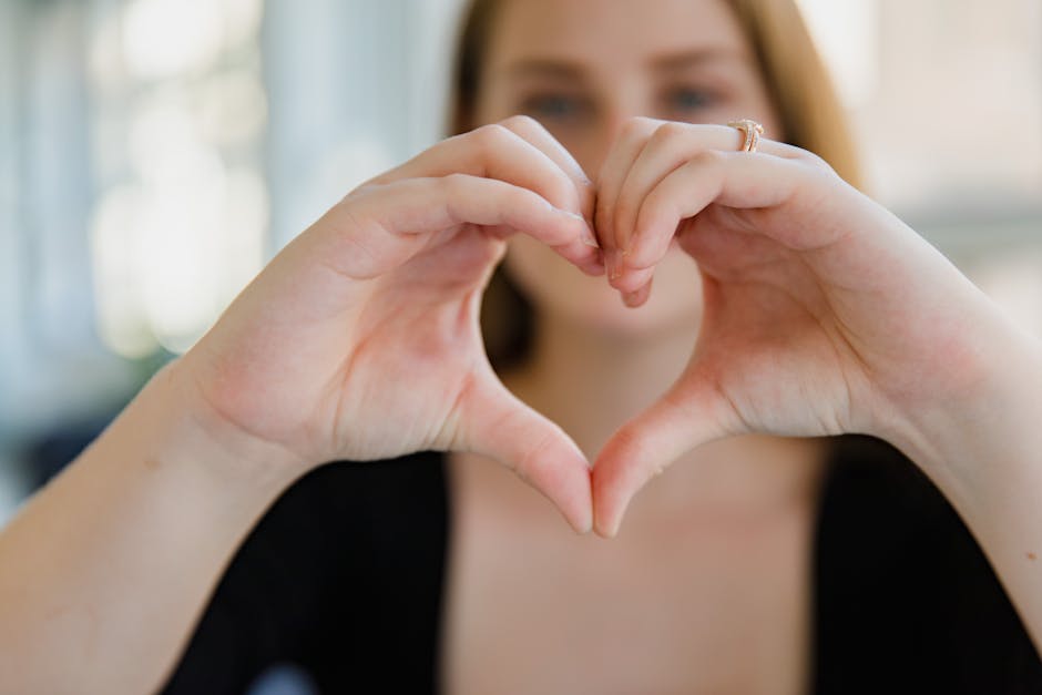 Close-up of a woman making a heart shape with her hands, symbolizing love.