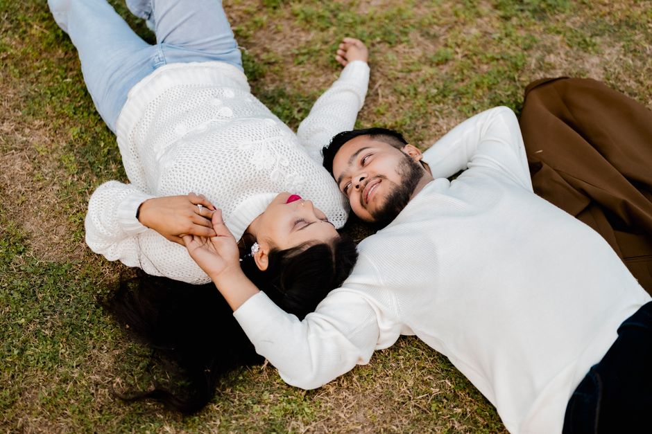 A loving Indian couple relaxes together on a grassy area, exuding warmth and romance.