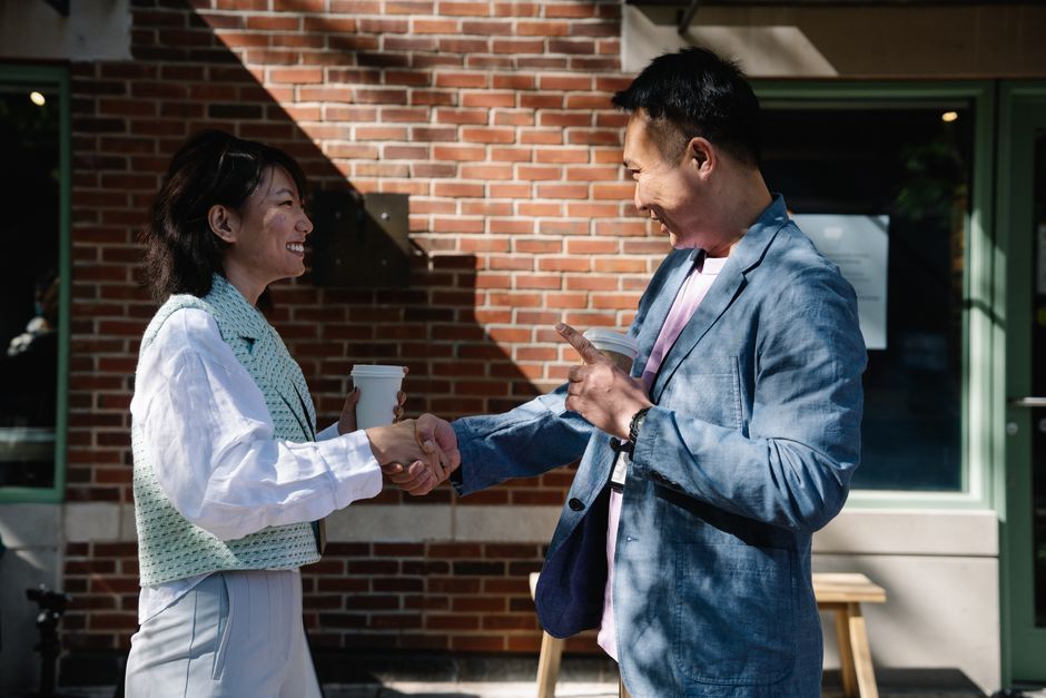 Two business colleagues shaking hands in a friendly outdoor meeting.