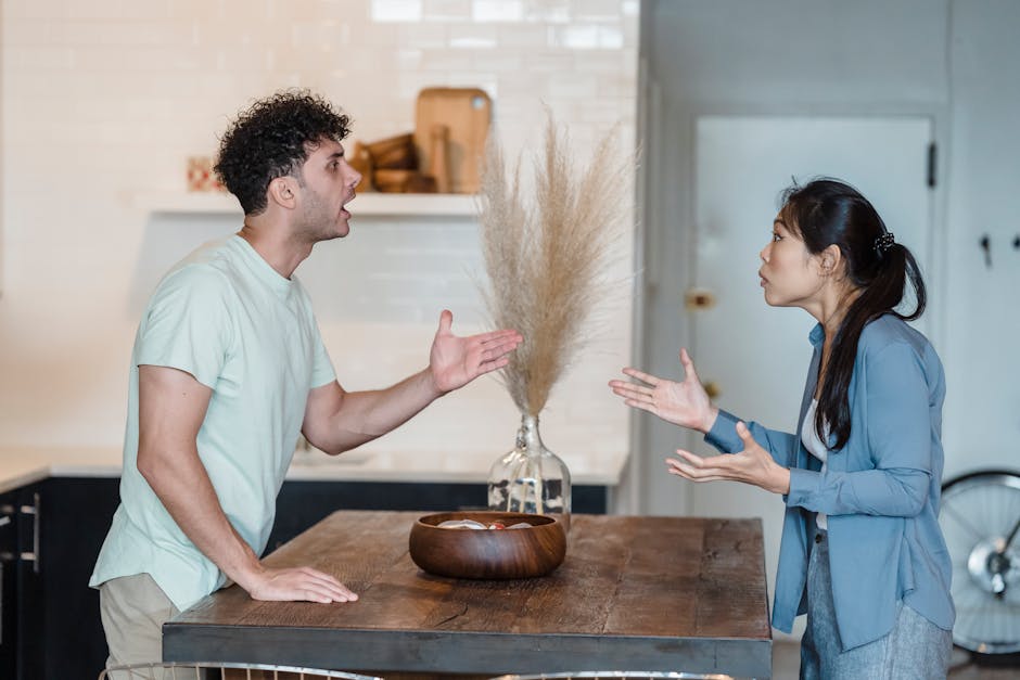 A couple engages in a heated argument at a wooden table in a modern indoor setting.