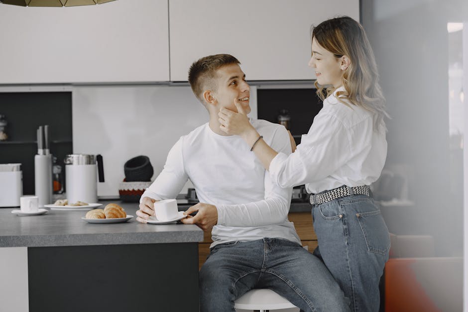 A couple shares a warm moment with coffee and pastries in a bright kitchen.
