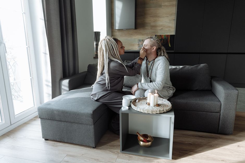 A couple engaging in a face painting ritual in a cozy living room setting, enhancing their connection.